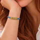 Close-up of NOUR sliding name bracelet with Dusty Blue satin cord