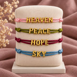 HEAVEN PEACE HOPE and SKY bracelets in four satin cord colours on a padded stand
