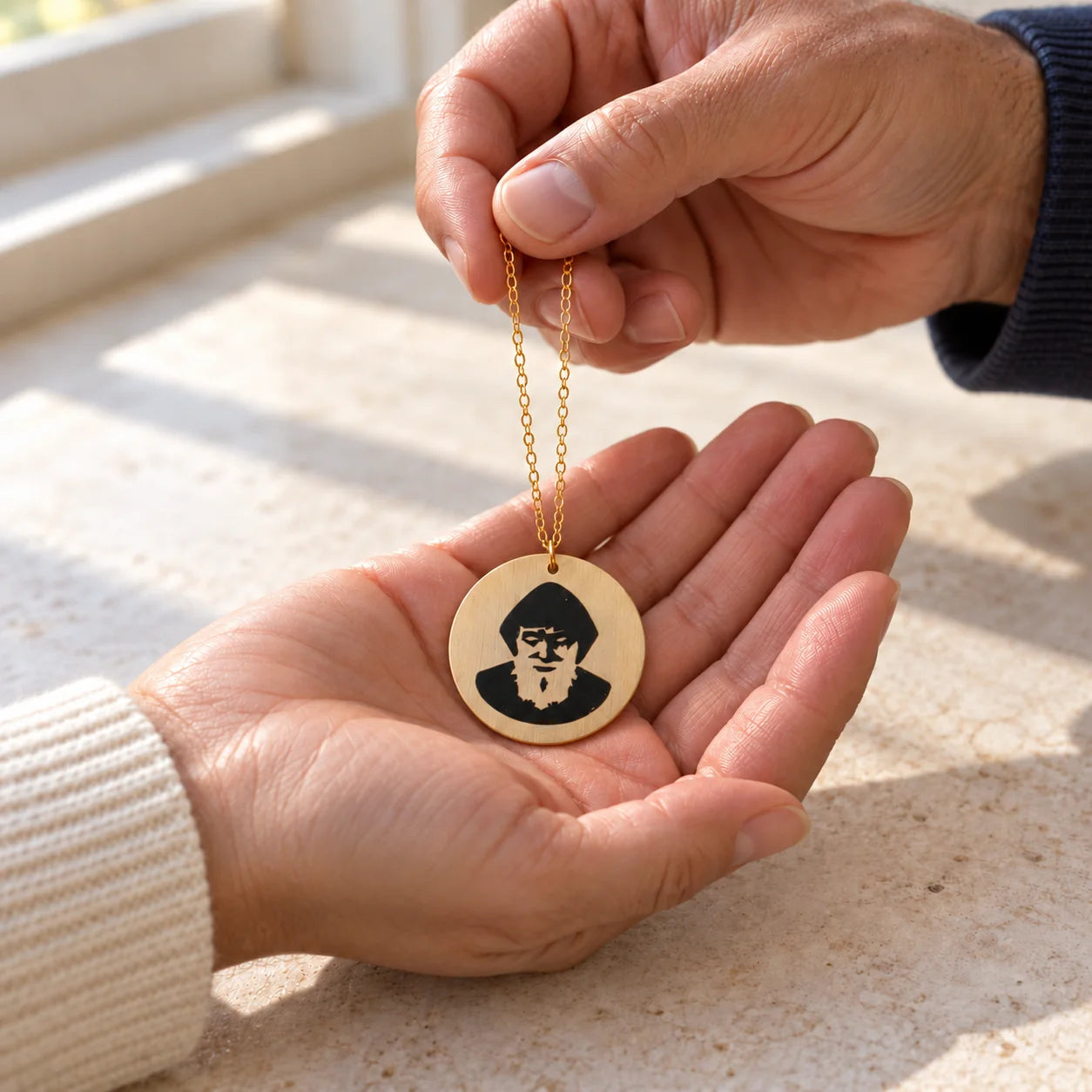 A St. Charbel necklace being placed in someone’s open hand.