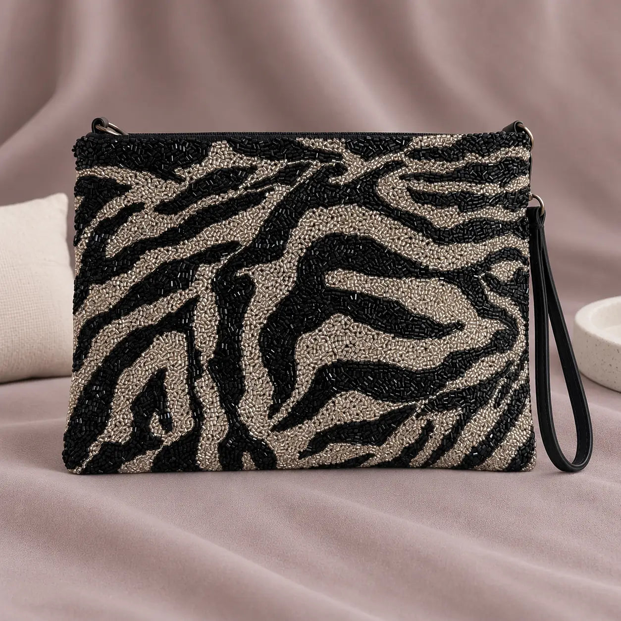 Zebra Beaded Clutch standing upright on muted mauve fabric with visible minimal white styling props