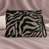 Zebra Beaded Clutch standing upright on muted mauve fabric with visible minimal white styling props