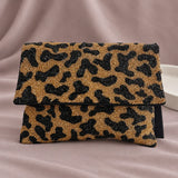 Tiger Beaded Clutch standing upright on muted mauve fabric with visible minimal white styling props