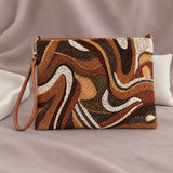 Sandy Beaded Clutch standing upright on muted mauve fabric with visible minimal white styling props