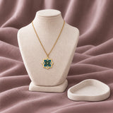 Oriental Flower Enamel Necklace – Teal & Grey — on an ivory display with mauve fabric and white styling props