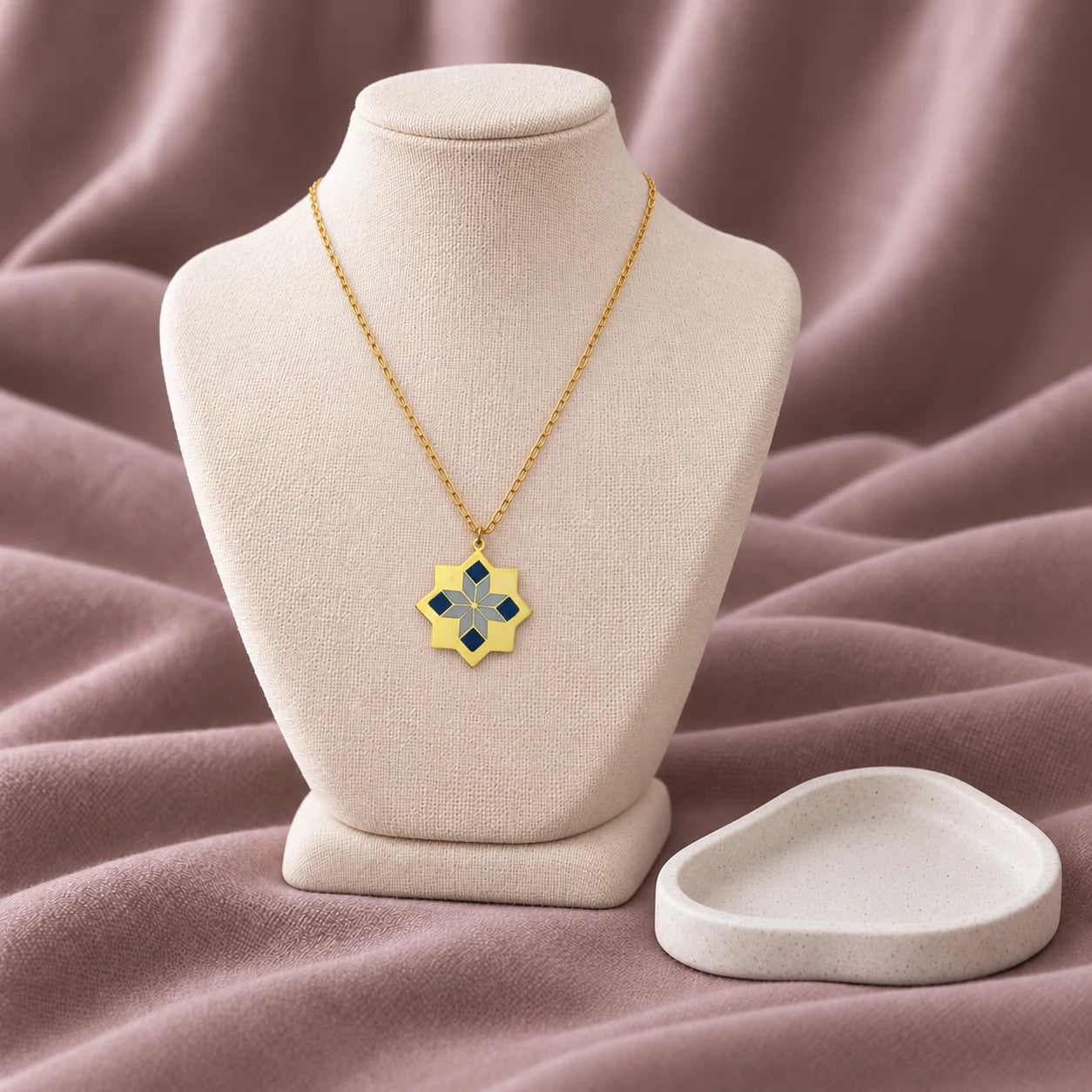 Oriental Flower Enamel Necklace – Navy & Grey — on an ivory display with mauve fabric and white styling props