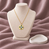 Oriental Flower Enamel Necklace – Navy & Grey — on an ivory display with mauve fabric and white styling props
