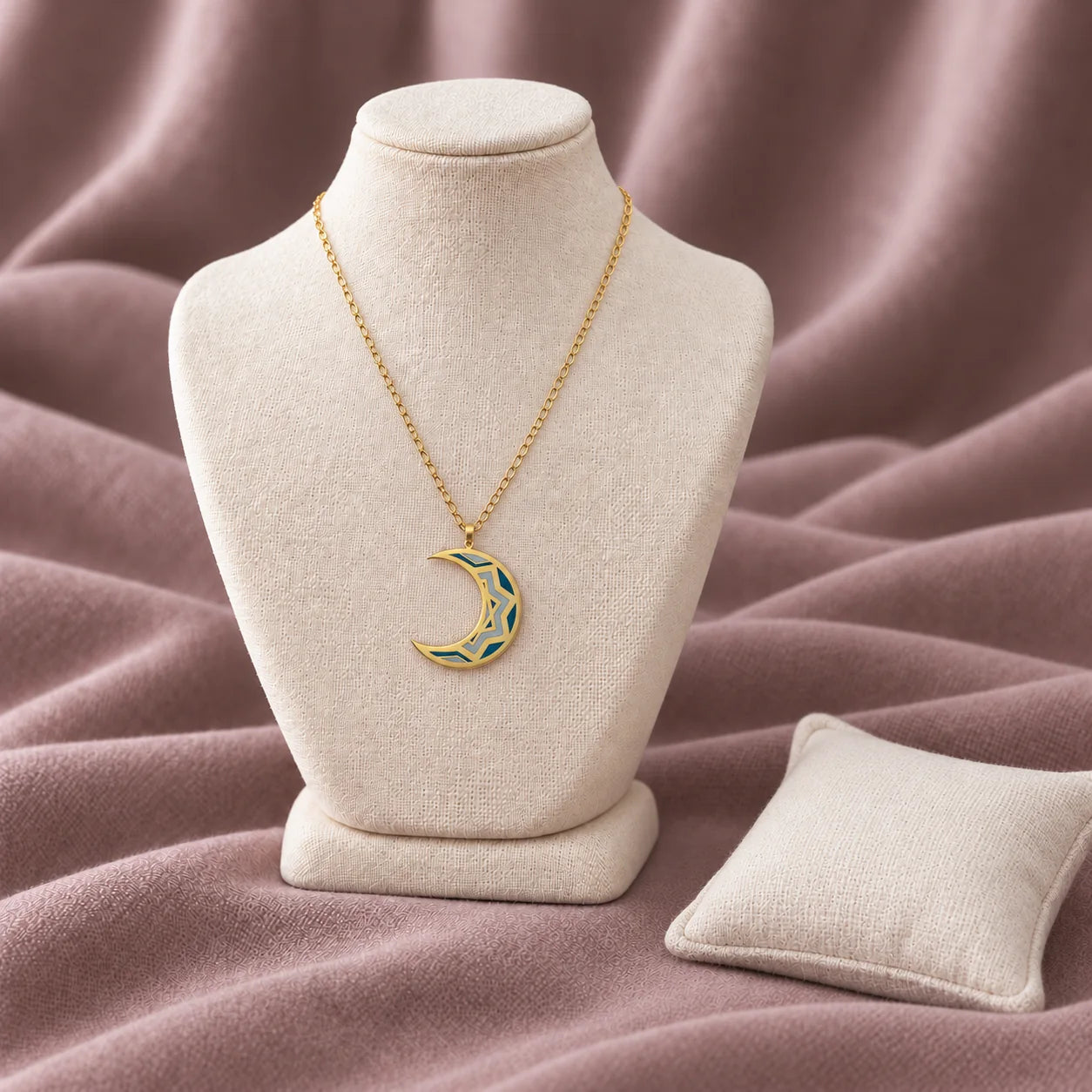 Oriental Moon Enamel Necklace — on an ivory display with mauve fabric and white styling props