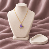 Purple Octopus Enamel Necklace — on an ivory display with mauve fabric and white styling props
