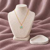Aqua Star Enamel Necklace — on an ivory display with mauve fabric and white styling props