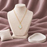 Shiny Shell Enamel Necklace — on an ivory display with mauve fabric and white styling props
